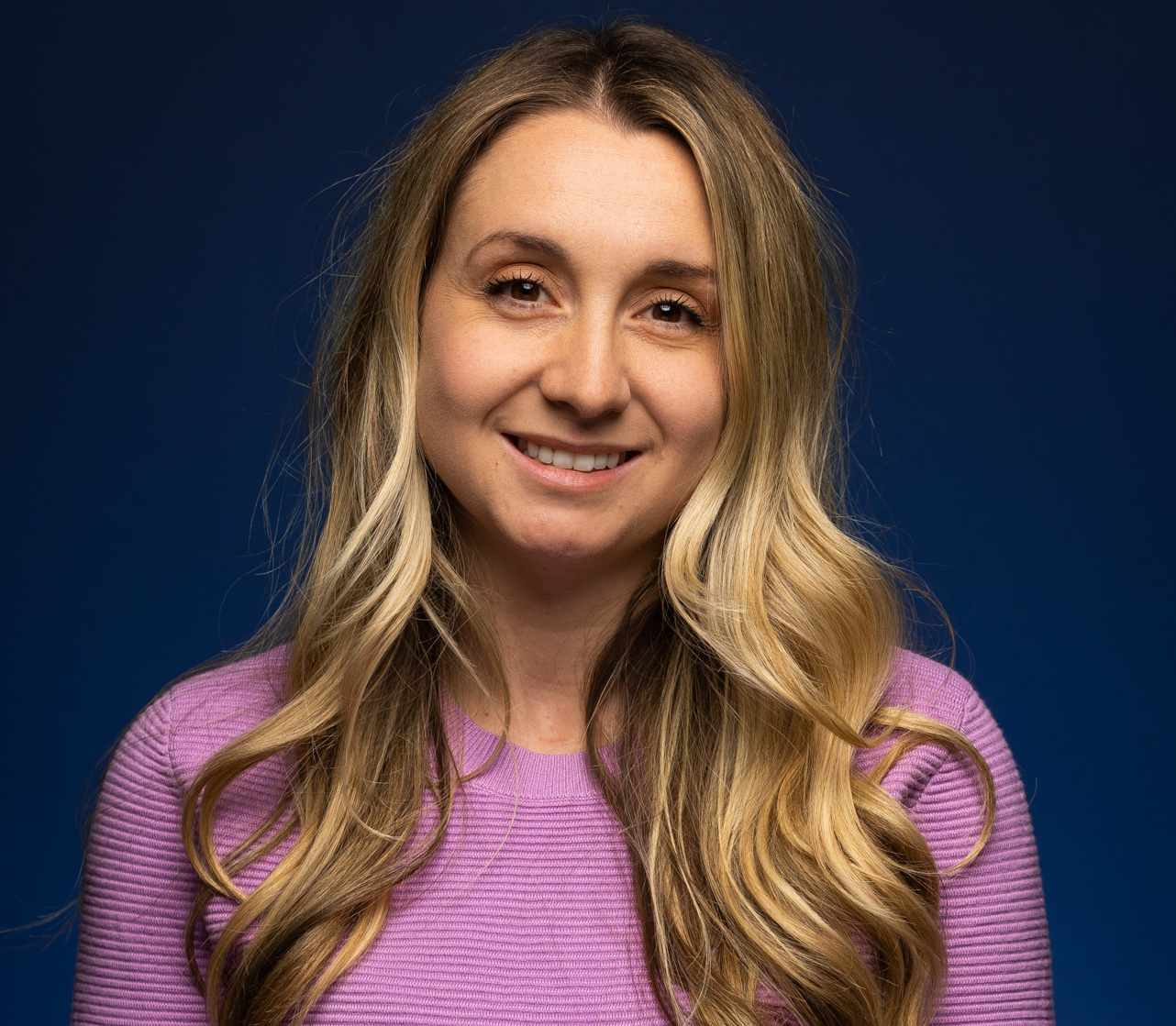 Emilie St-Aubin posing in front of a dark blue background.